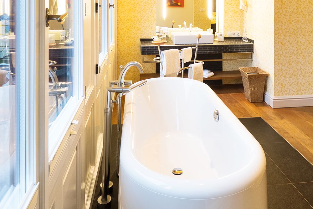 Ein geräumiges Badezimmer mit einer freistehenden Badewanne in der Mitte, Doppelwaschbecken mit Spiegel und Holzboden.