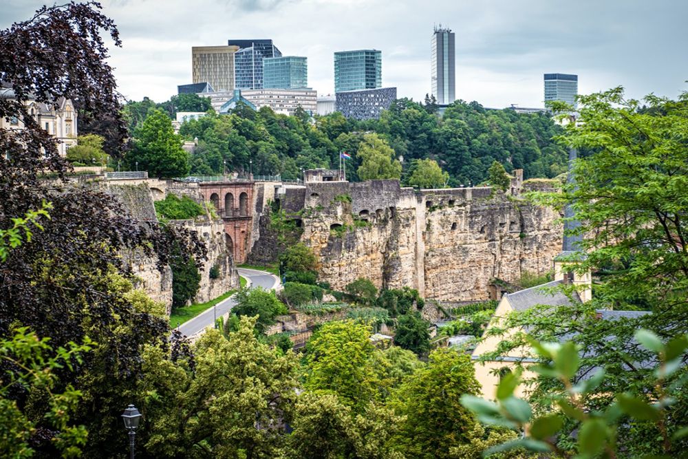 Erkunden Sie die Ruinen der Bock-Kasematten in Luxemburg-Stadt, wo historischer Charme auf Natur trifft und moderne Gebäude unter einem wolkigen Himmel hervorschauen. In der Nähe können Sie shoppen gehen oder an spannenden Stadttouren teilnehmen, um Ihr Erlebnis zu bereichern.